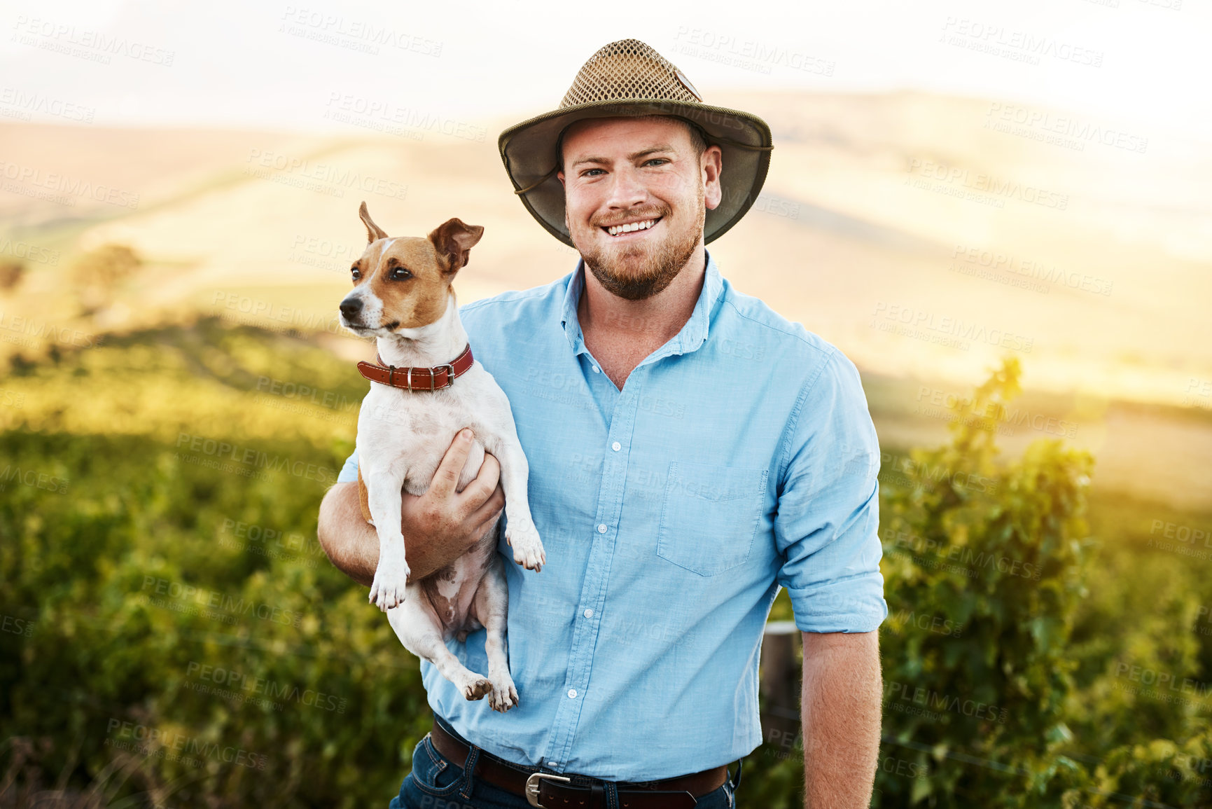 Buy stock photo Portrait of a farmer holding his dog in a vineyard