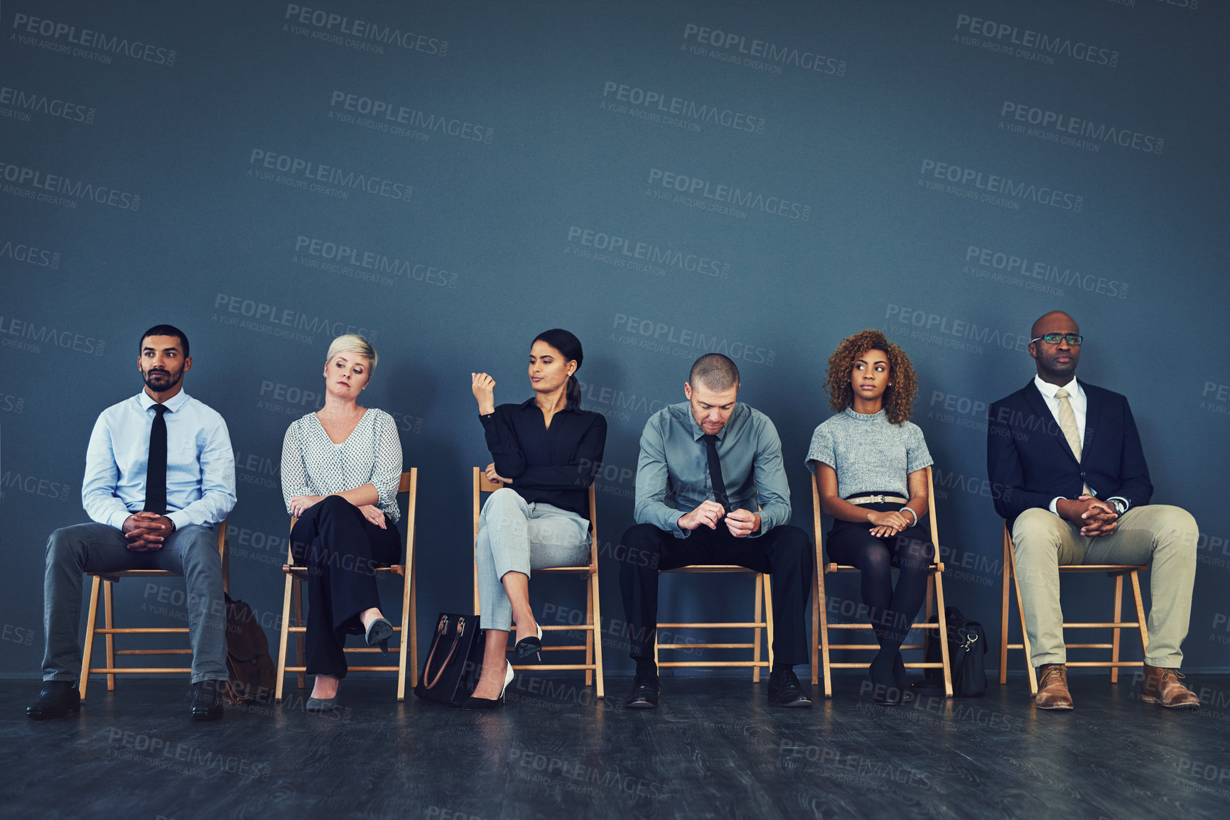 Buy stock photo Shot of a group of well dressed businesspeople seated in line while waiting to be interview