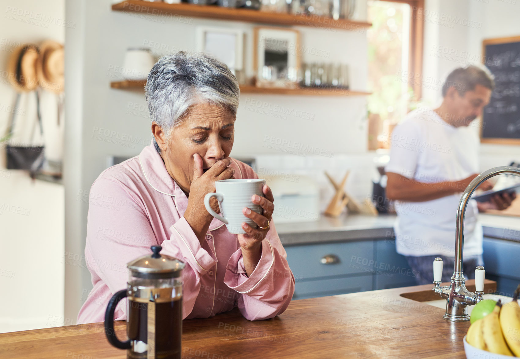 Buy stock photo Shot of a carefree elderly woman sitting at a table in the kitchen drinking coffee and about to sneeze