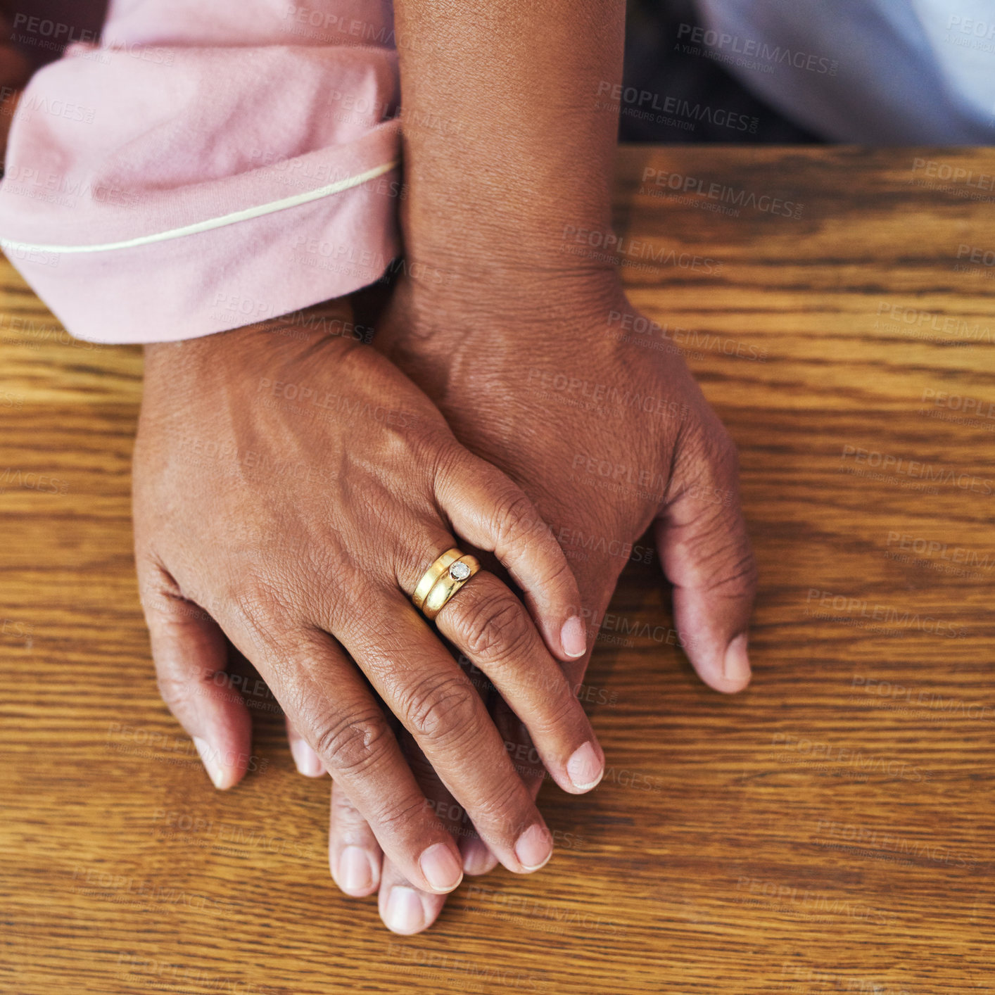 Buy stock photo High angle closeup of an unrecognizable couple holding hands on a table at home during the day
