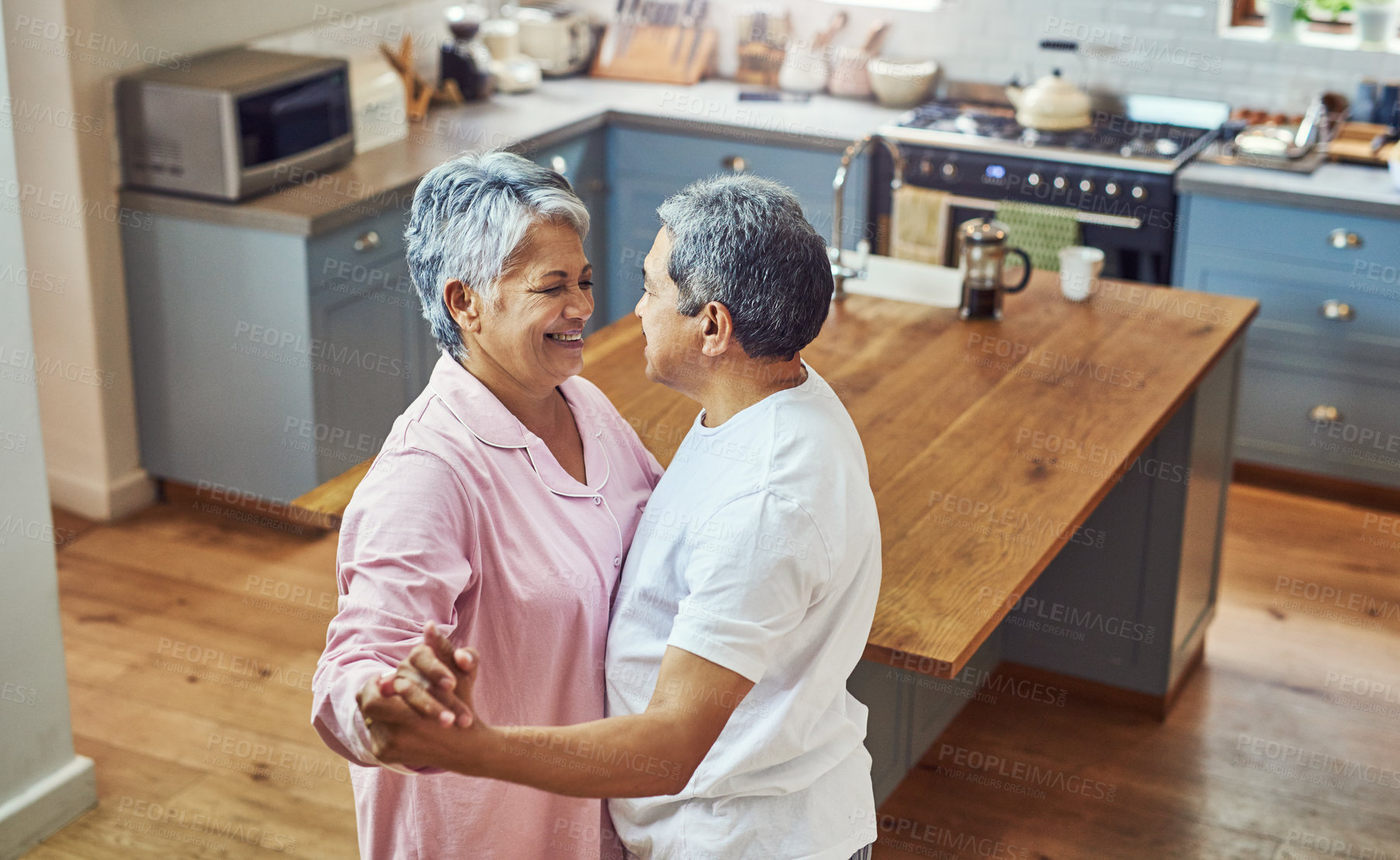 Buy stock photo Shot of a carefree elderly couple having a dance inside of the kitchen at home during the day