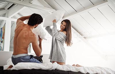 Buy stock photo Shot of a young couple having a pillow fight in their bedroom at home