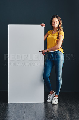 Buy stock photo Shot of a beautiful young woman standing next to a blank placard
