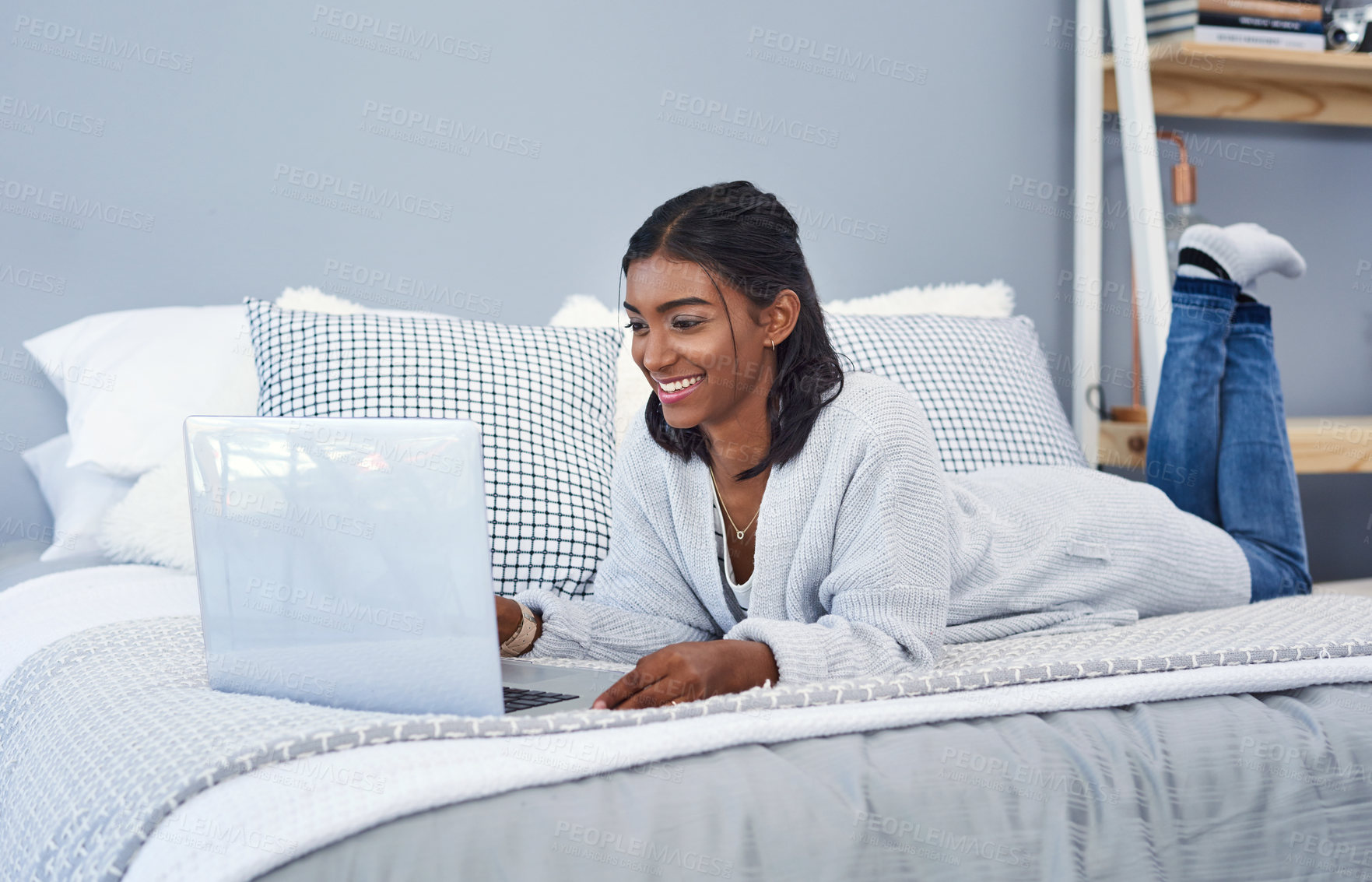 Buy stock photo Shot of an attractive young woman using a laptop and chilling on her bed in her bedroom at home
