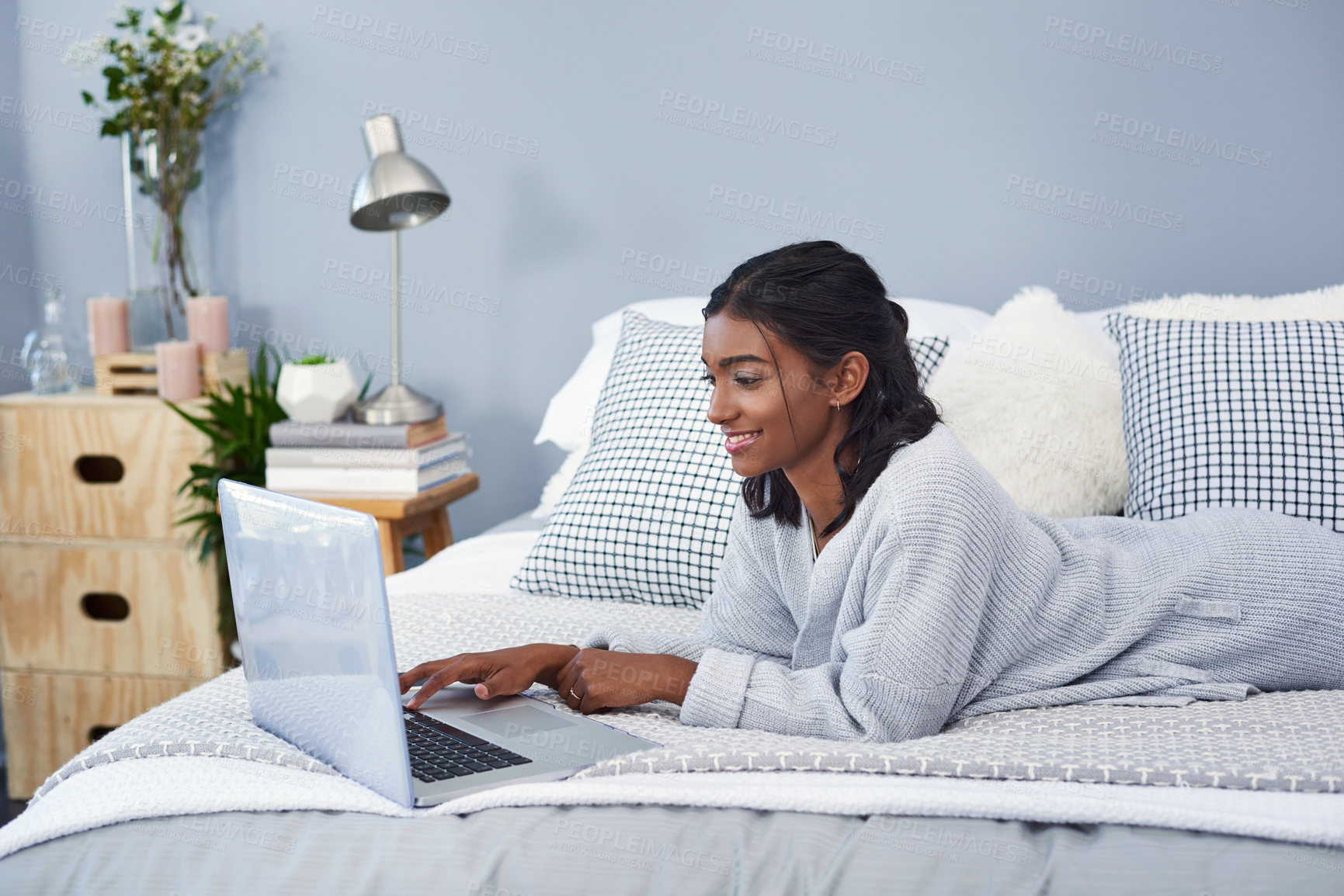 Buy stock photo Shot of an attractive young woman using a laptop while chilling on her bed in her bedroom at home
