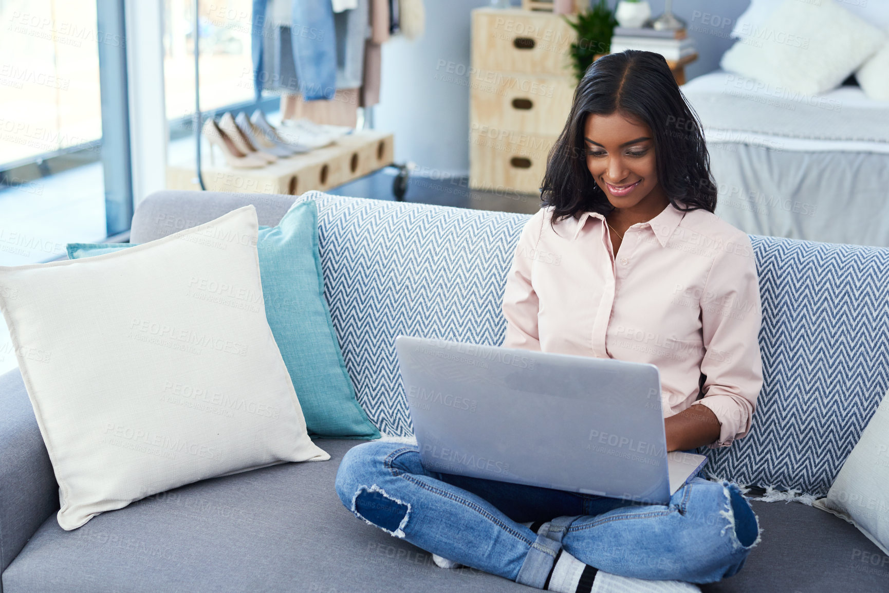 Buy stock photo Shot of an attractive young woman using a laptop while chilling on the sofa in the living room at home