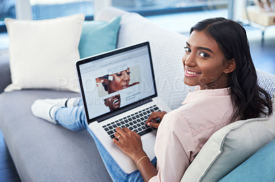 Buy stock photo Shot of an attractive young woman using a laptop while chilling on the sofa in the living room at home