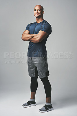 Buy stock photo Studio portrait of an athletic young man standing with his arms crossed against a grey background
