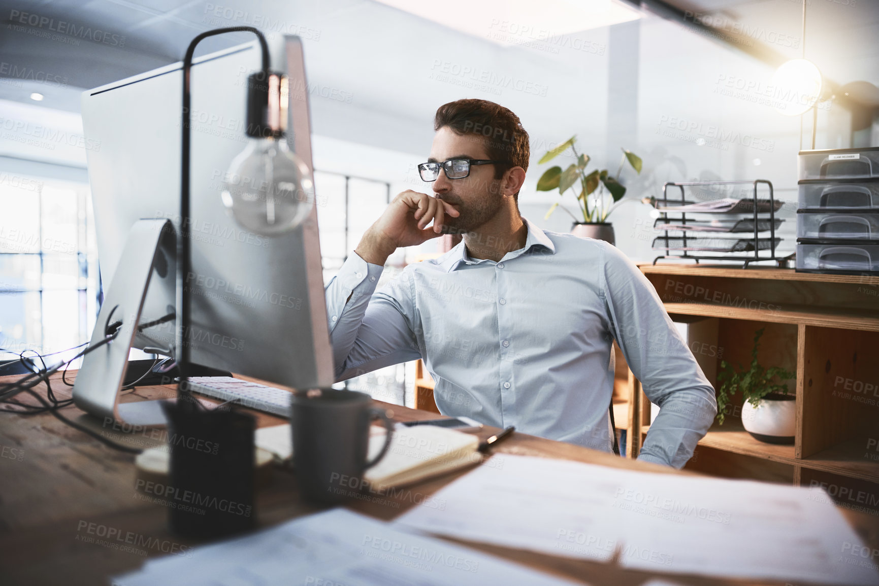 Buy stock photo Shot of a young businessman working late on a computer in an office