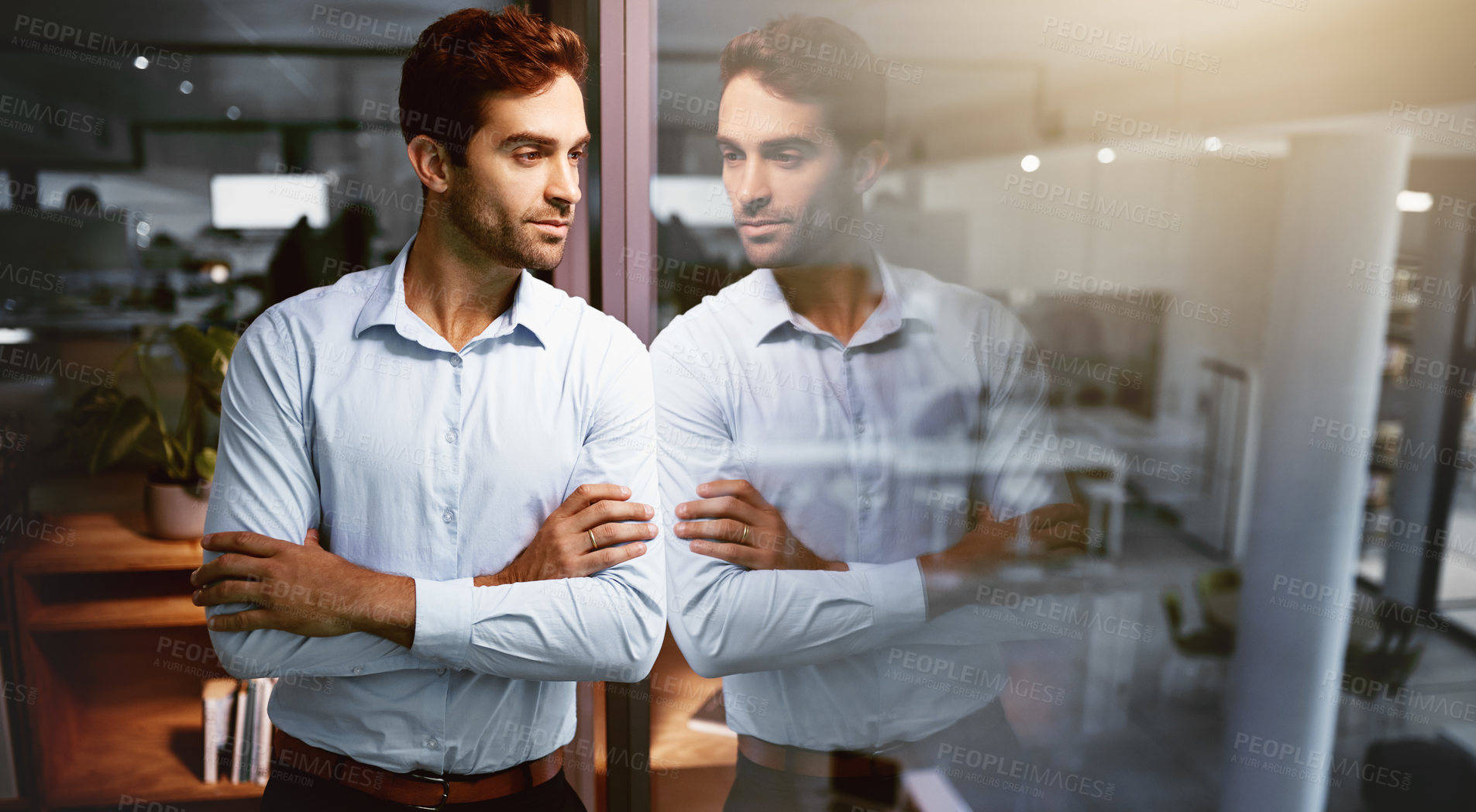 Buy stock photo Shot of a young businessman standing in an office at night