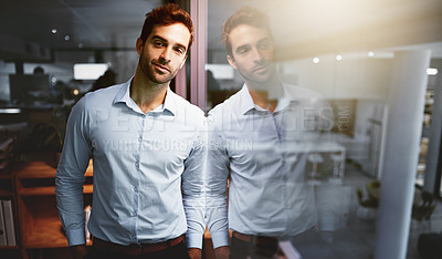 Buy stock photo Portrait of a young businessman standing in an office at night