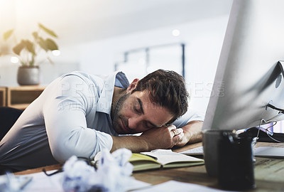 Buy stock photo Shot of a young businessman sleeping at his desk while working late in an office