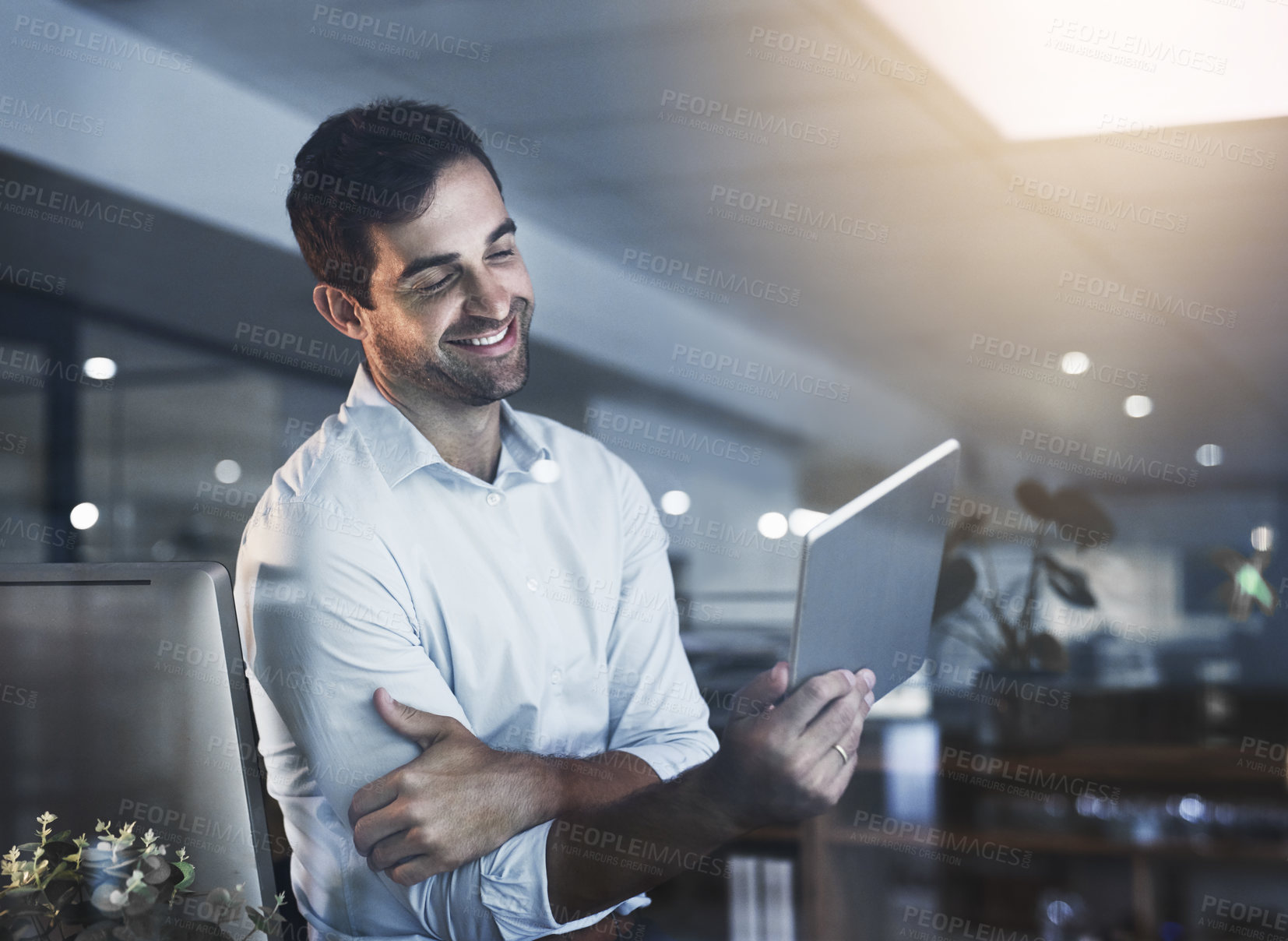 Buy stock photo Shot of a young businessman working late on a digital tablet in an office