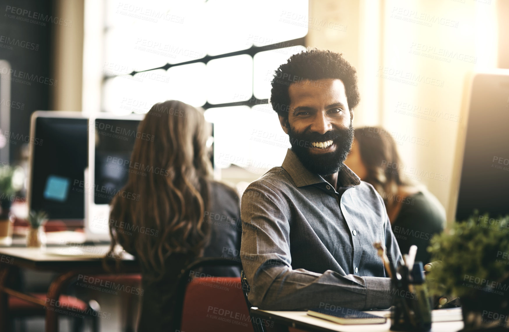 Buy stock photo Shot of a handsome businessman sitting at his desk in a modern office