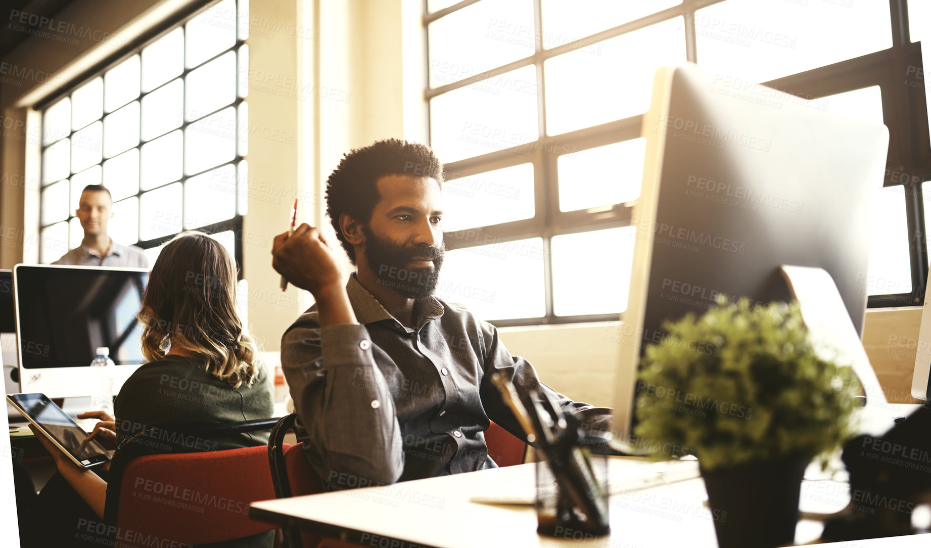 Buy stock photo Shot of a handsome businessman sitting at his desk in a modern office