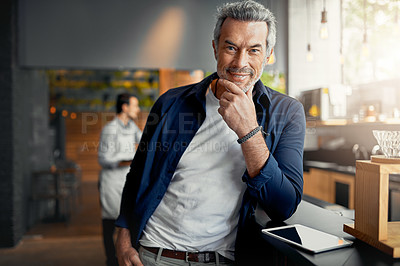 Buy stock photo Cropped portrait of a handsome mature man standing wth his hand on his chin in his coffee shop