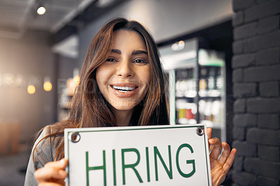 Buy stock photo Cropped portrait of an attractive young woman holding up a hiring sign while standing in her coffee shop
