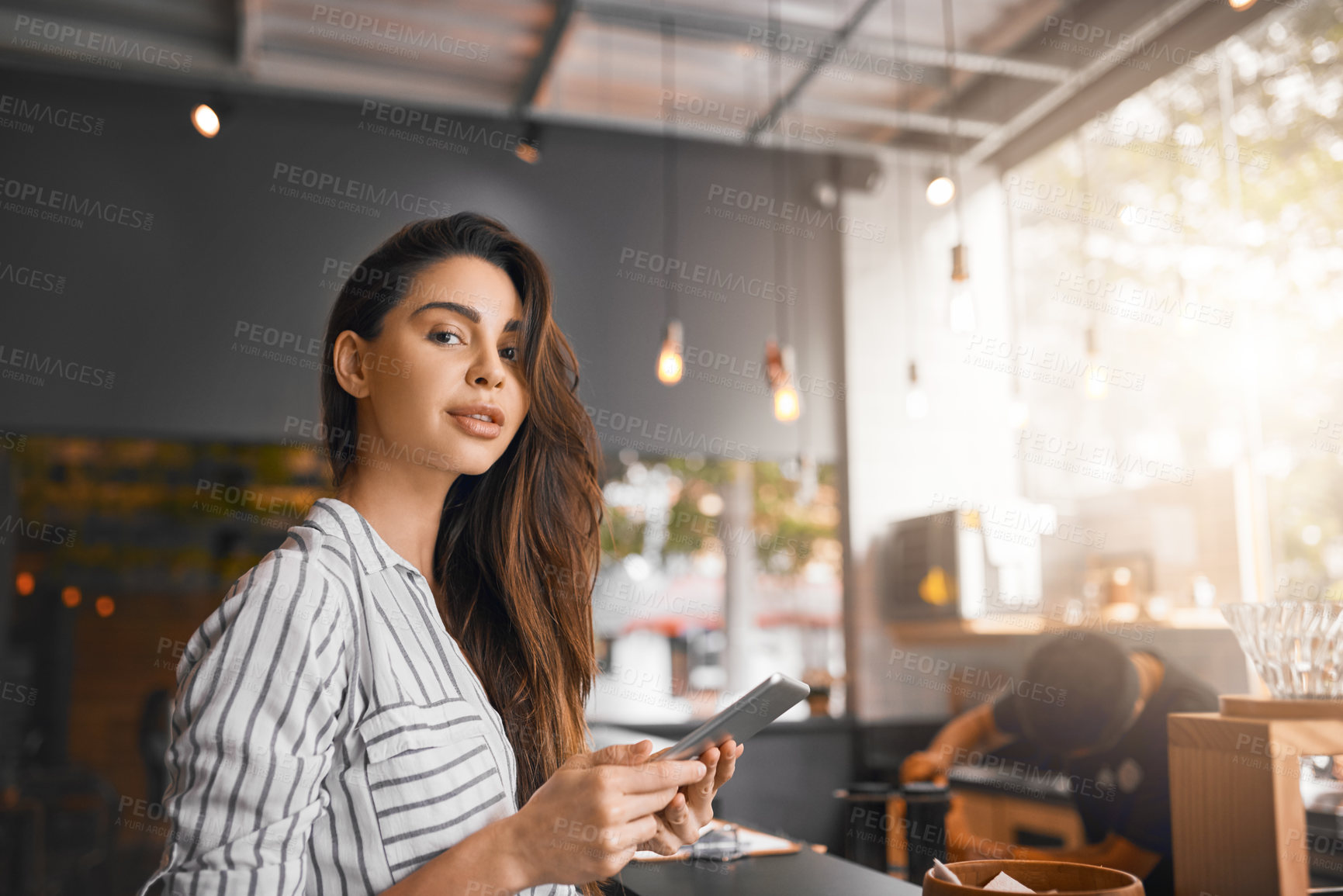 Buy stock photo Cropped portrait of an attractive young woman working on a digital tablet while standing in her coffee shop