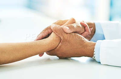 Buy stock photo Closeup of a doctor holding a patient's hands in comfort inside of a hospital during the day