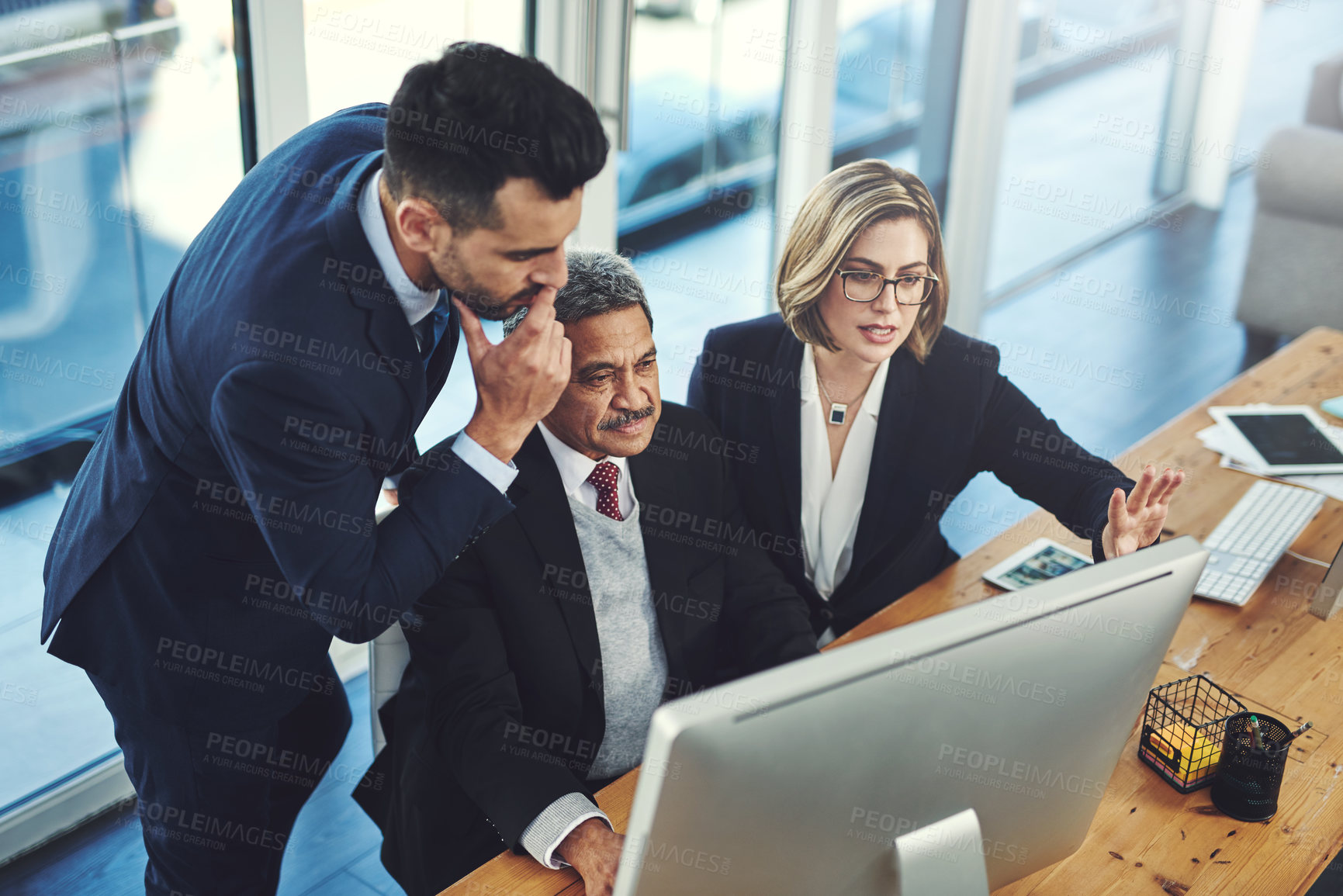 Buy stock photo Shot of a group of businesspeople working together on a computer in an office