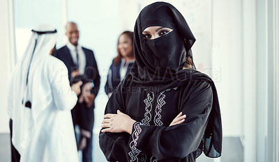 Buy stock photo Cropped portrait of an attractive young arabic businesswoman standing with her arms crossed in the office with her colleagues in the background