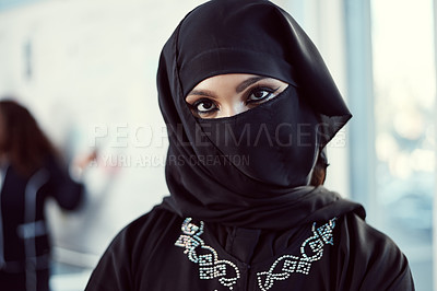 Buy stock photo Cropped portrait of an attractive young arabic businesswoman standing with her arms crossed in the office with her colleagues in the background