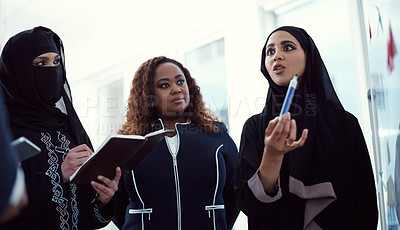 Buy stock photo Low angle shot of a group of diverse business colleagues working together on a whiteboard in their office