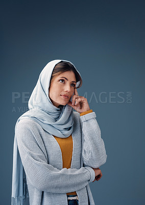 Buy stock photo Thinking, serious and muslim woman with idea in studio isolated on a blue background mockup space. Fashion, dream and Islamic person in hijab for vision, inspiration or decision for planning future
