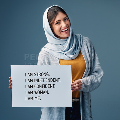 Buy stock photo Muslim, woman and happy with poster in studio on blue background for equality, empowerment and activist. Female person, card and smile in confidence for human right campaign and advocate in portrait