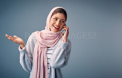Buy stock photo Talking, phone call and muslim woman with smartphone in studio for conversation, networking or gossip on blue background. Contact, happy and Arab person with for chatting,  speaking or discussion 