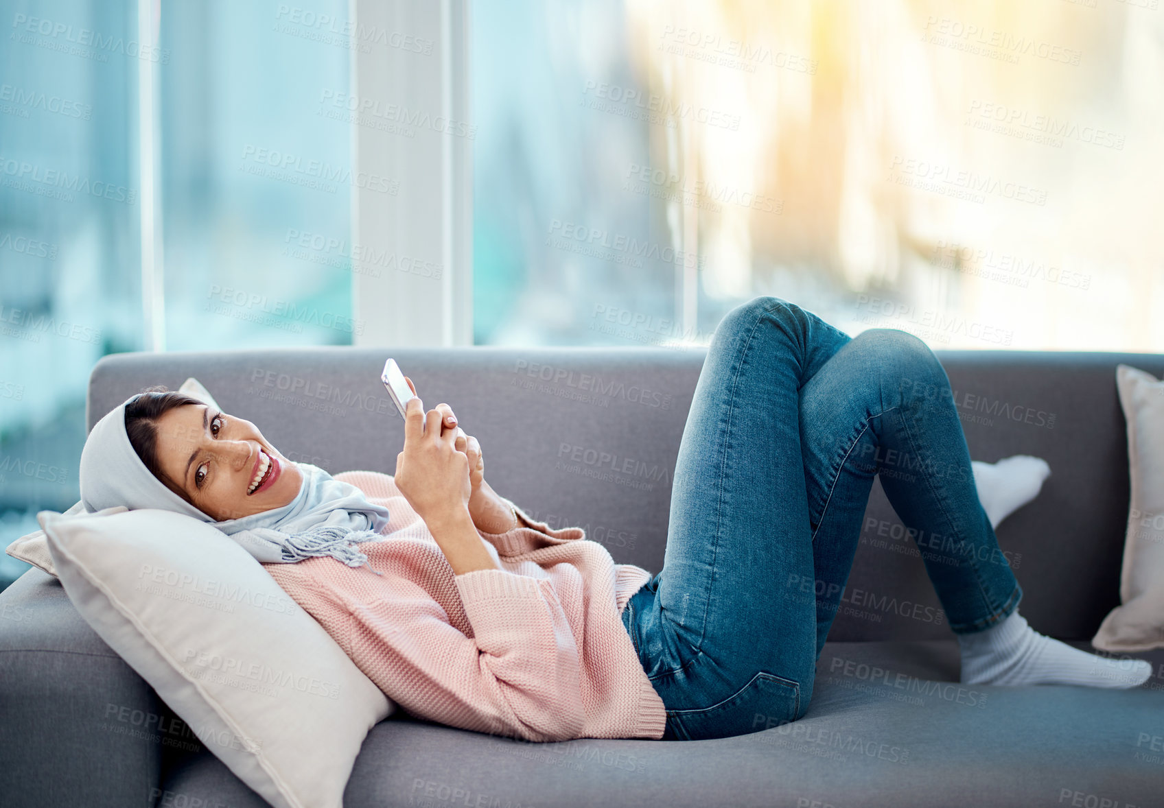 Buy stock photo High angle portrait of an attractive young woman sending a text while chilling on her sofa at home
