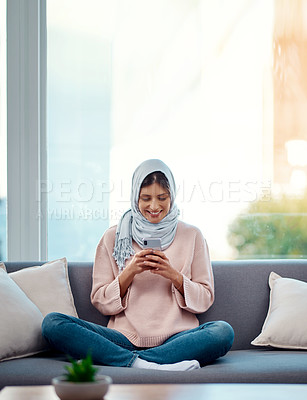 Buy stock photo Full length shot of an attractive young woman sending a text while chilling on her sofa at home