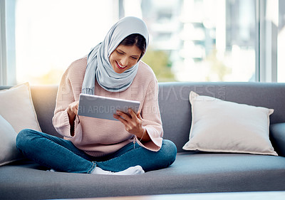 Buy stock photo Smile, reading and muslim woman with tablet on sofa for online ebook in living room at home. Happy, relax and islamic female person enjoying internet story, novel or literature on digital technology