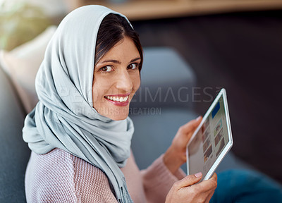 Buy stock photo Happy, reading and muslim woman with tablet on sofa for choosing online ebook in living room at home. Relax, digital technology and islamic female person decide on story, novel or literature in house