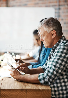 Buy stock photo Shot of a businessman using a digital tablet during a boardroom meeting