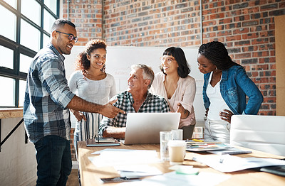 Buy stock photo Shot of a group of colleagues using a laptop together in a modern office