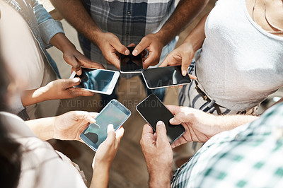Buy stock photo Cropped shot of a group of colleagues using their cellphone while standing in a circle