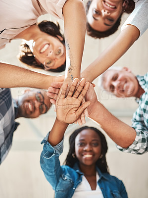 Buy stock photo Low angle shot of a group of creatives stacking their hands in unity