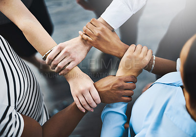 Buy stock photo High angle shot of a group of businesspeople holding one another's wrists in a circular formation