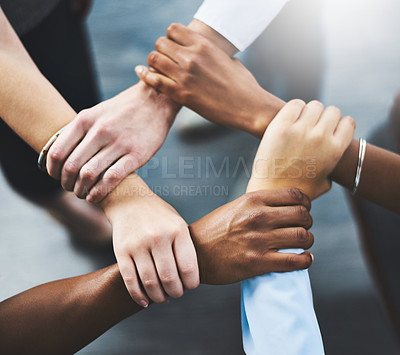 Buy stock photo High angle shot of a group of businesspeople holding one another's wrists in a circular formation