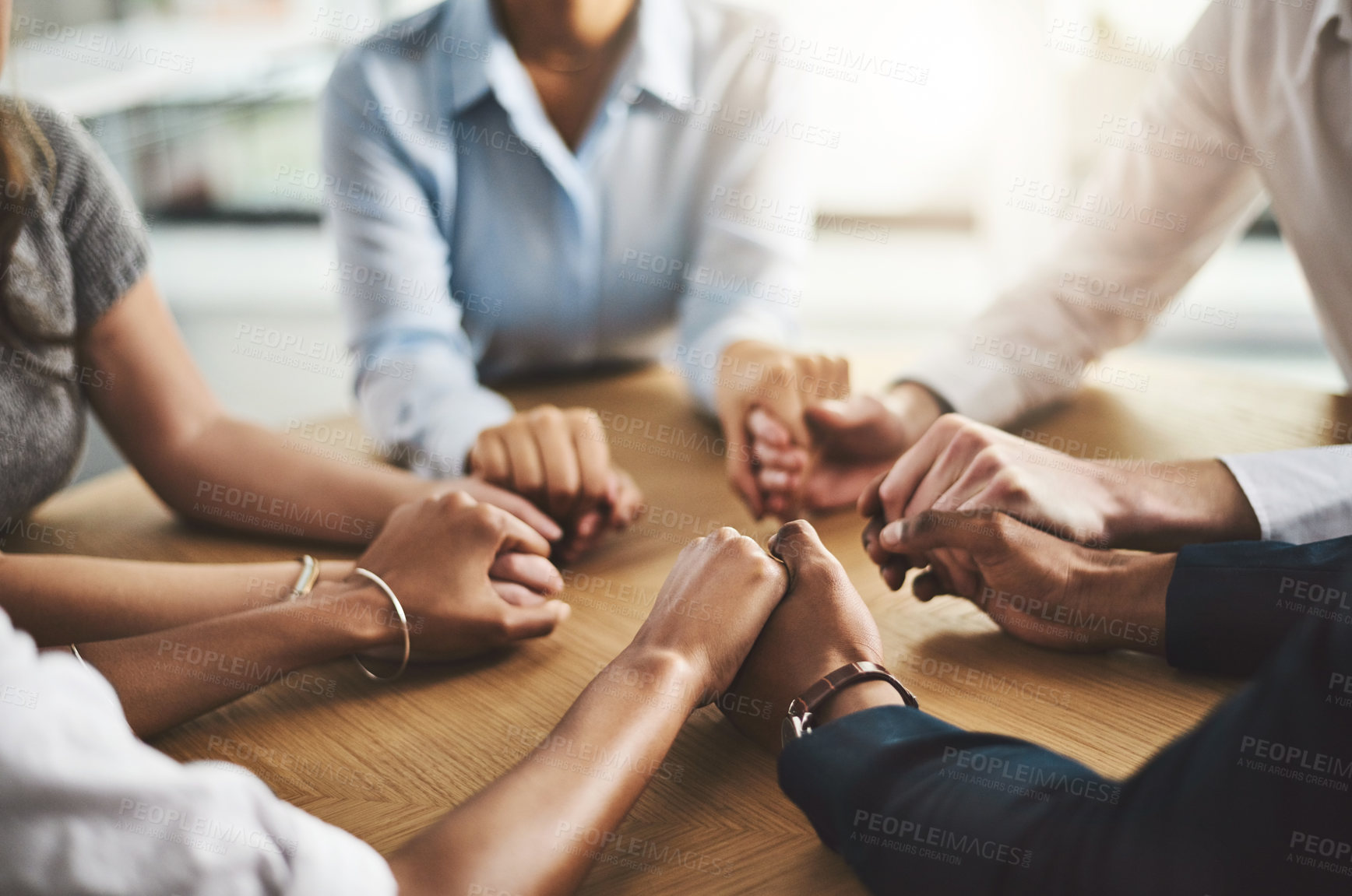 Buy stock photo Closeup shot of a group of businesspeople sitting together at a table and holding hands