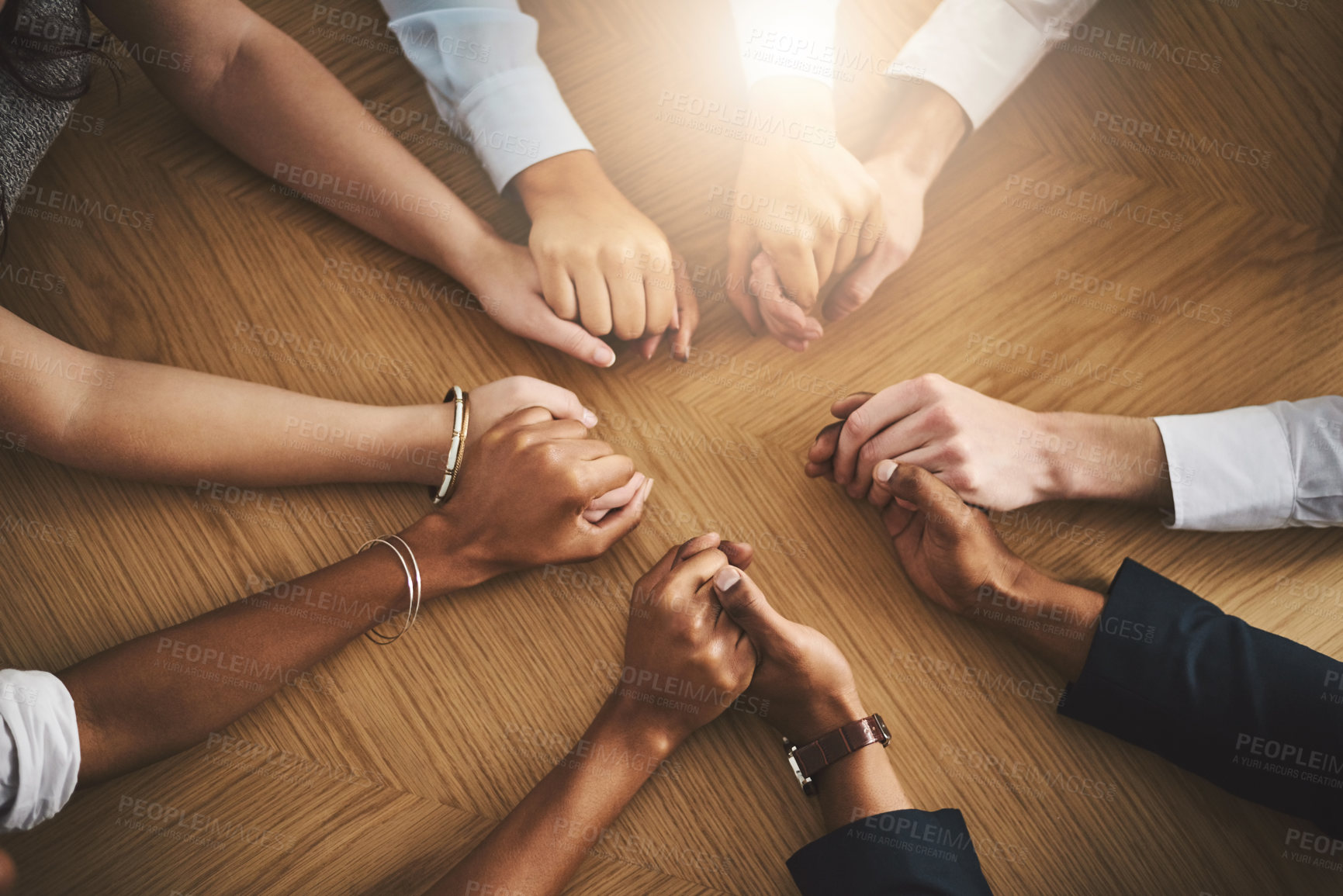 Buy stock photo Support, diversity and people holding hands by a table at a group counseling or therapy session. Gratitude, trust and friends in a circle for praying together for religion, community and connection.
