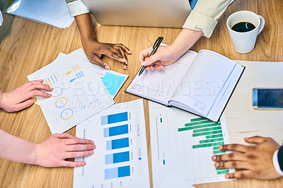 Buy stock photo High angle shot of a group of unrecognizable businesspeople making notes and looking at graphs inside the office at work during the day