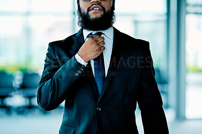 Buy stock photo Shot of an unrecognizable businessman adjusting his tie in the office during the day
