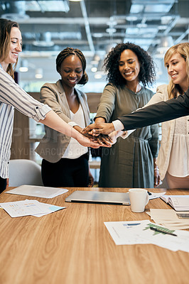 Buy stock photo Shot of a cheerful group of businesspeople forming a huddle with their hands inside of the office at work during the day