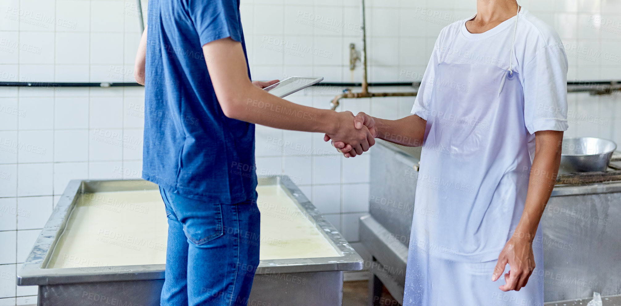 Buy stock photo Cropped shot of two people shaking hands in a cheese factory