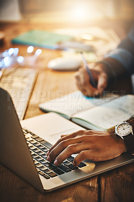 Buy stock photo Hand, typing and man on a laptop while writing research notes for creative project at night. Planning, professional and closeup of male employee working overtime with computer and notebook in office.