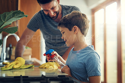 Buy stock photo Shot of a father and son cleaning the kitchen counter together at home