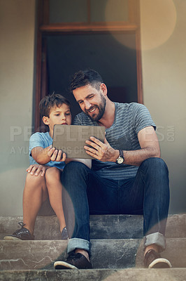 Buy stock photo Shot of a father and son using a digital tablet together on the front steps of their home