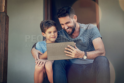 Buy stock photo Shot of a father and son using a digital tablet together on the front steps of their home